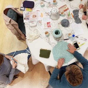 3 personnes en train de crocheter | vue de dessus | table avec ouvrages en cours